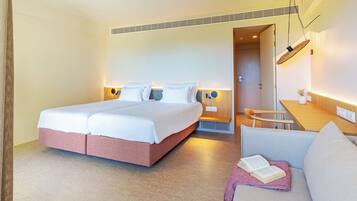 A hotel room with a double bed, a sofa, a small table, and a desk.