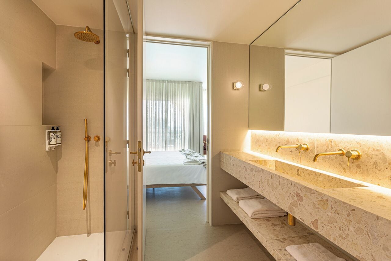 Un baño moderno con ducha envuelta en vidrio, un espejo grande y encimera de mármol.