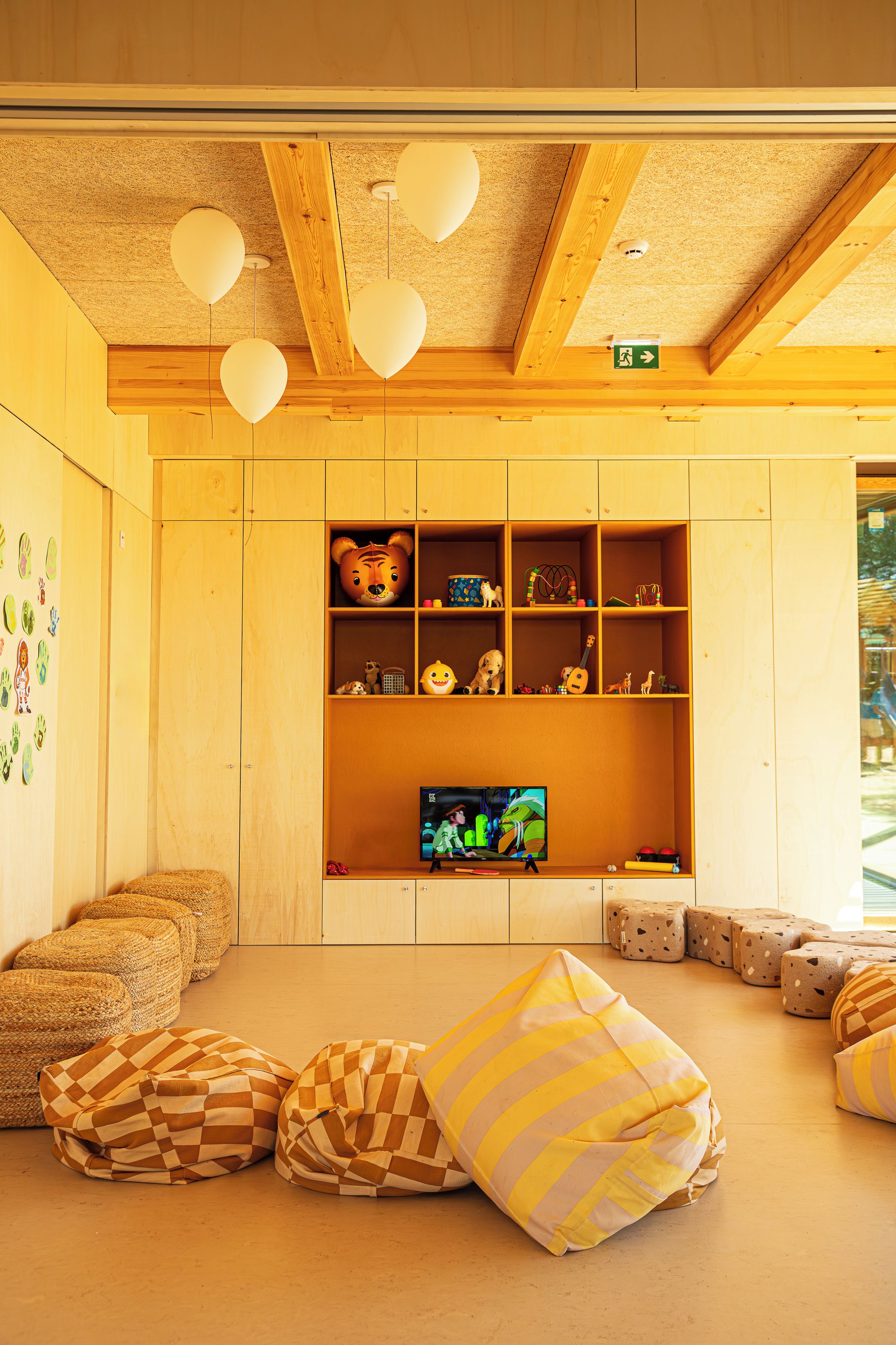 Una habitación acogedora con paredes de madera, un televisor y varios juguetes y cojines.