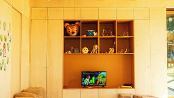 Una habitación acogedora con paredes de madera, un televisor y varios juguetes y cojines.