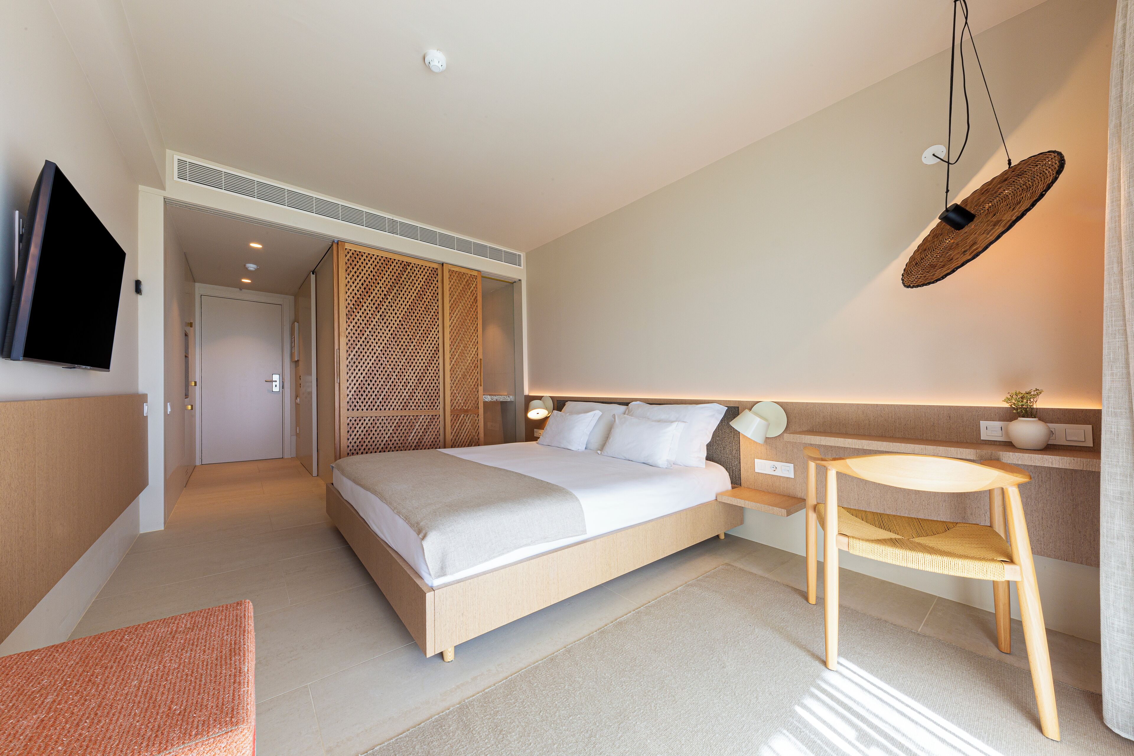 Une chambre d’hôtel moderne avec un grand lit, une table de chevet et un petit bureau avec une chaise.