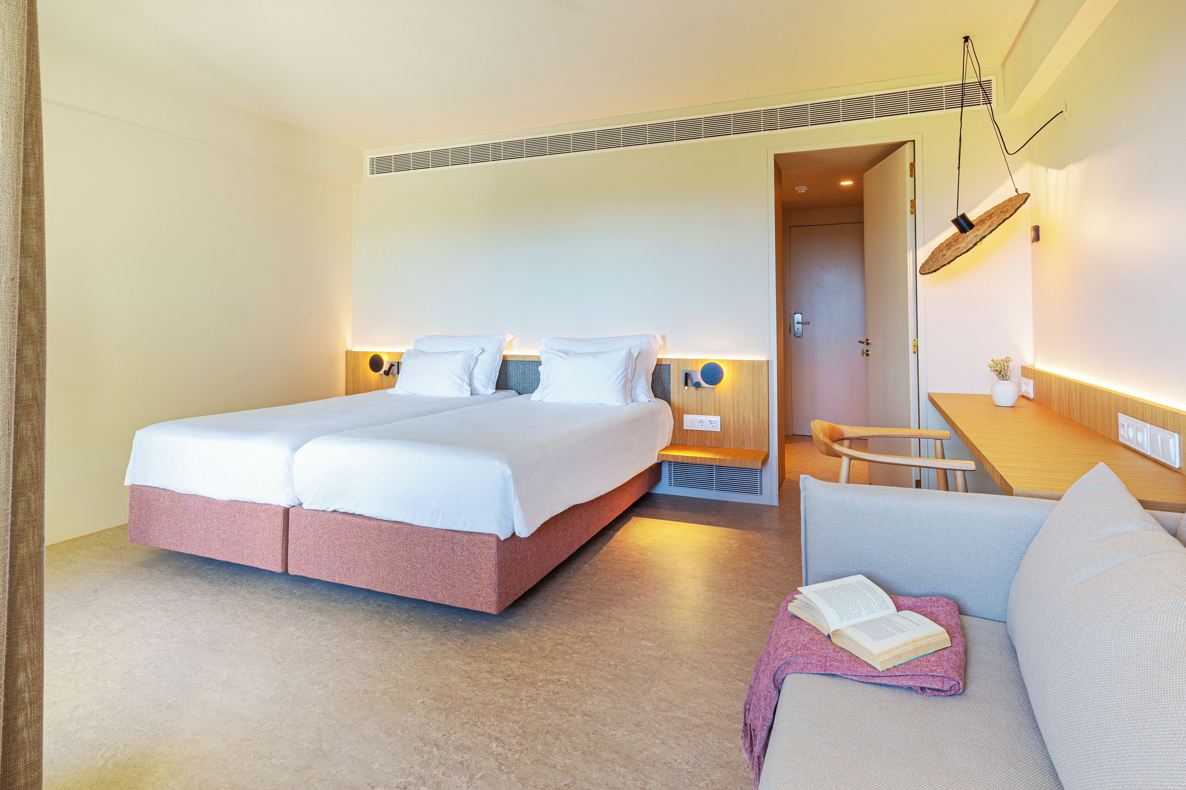 Une chambre d’hôtel avec un lit double, une petite table, un canapé et une lampe de lecture.