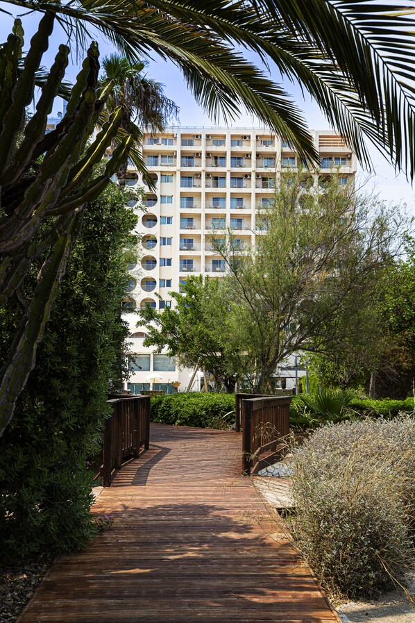 A wooden pathway leading to a multi-story building with balconies and air conditioning units. - Ozadi Altura Beach Resort  (Castro Marim)