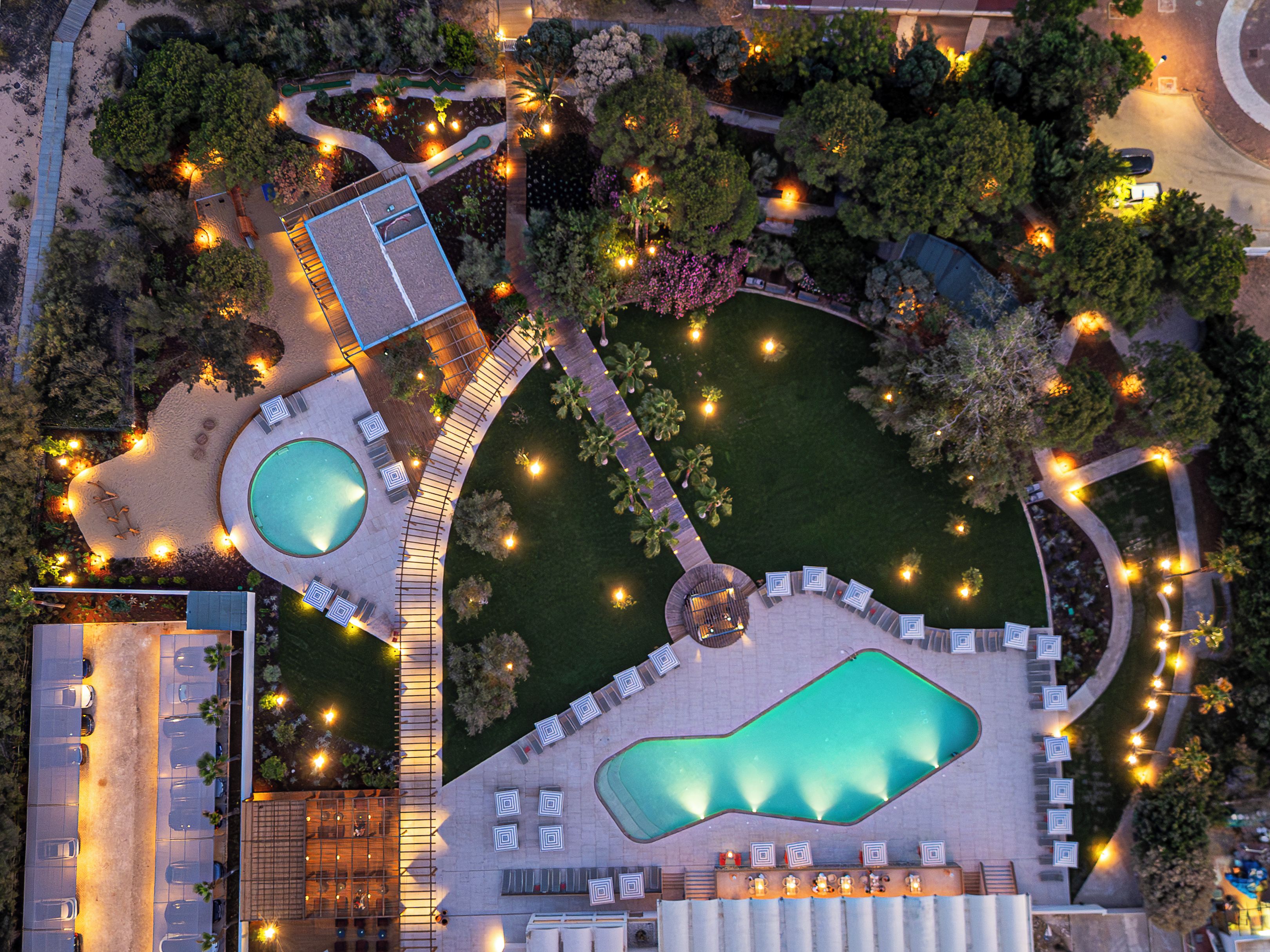 Vista aérea de um resort com várias piscinas, áreas de descanso e estacionamento.