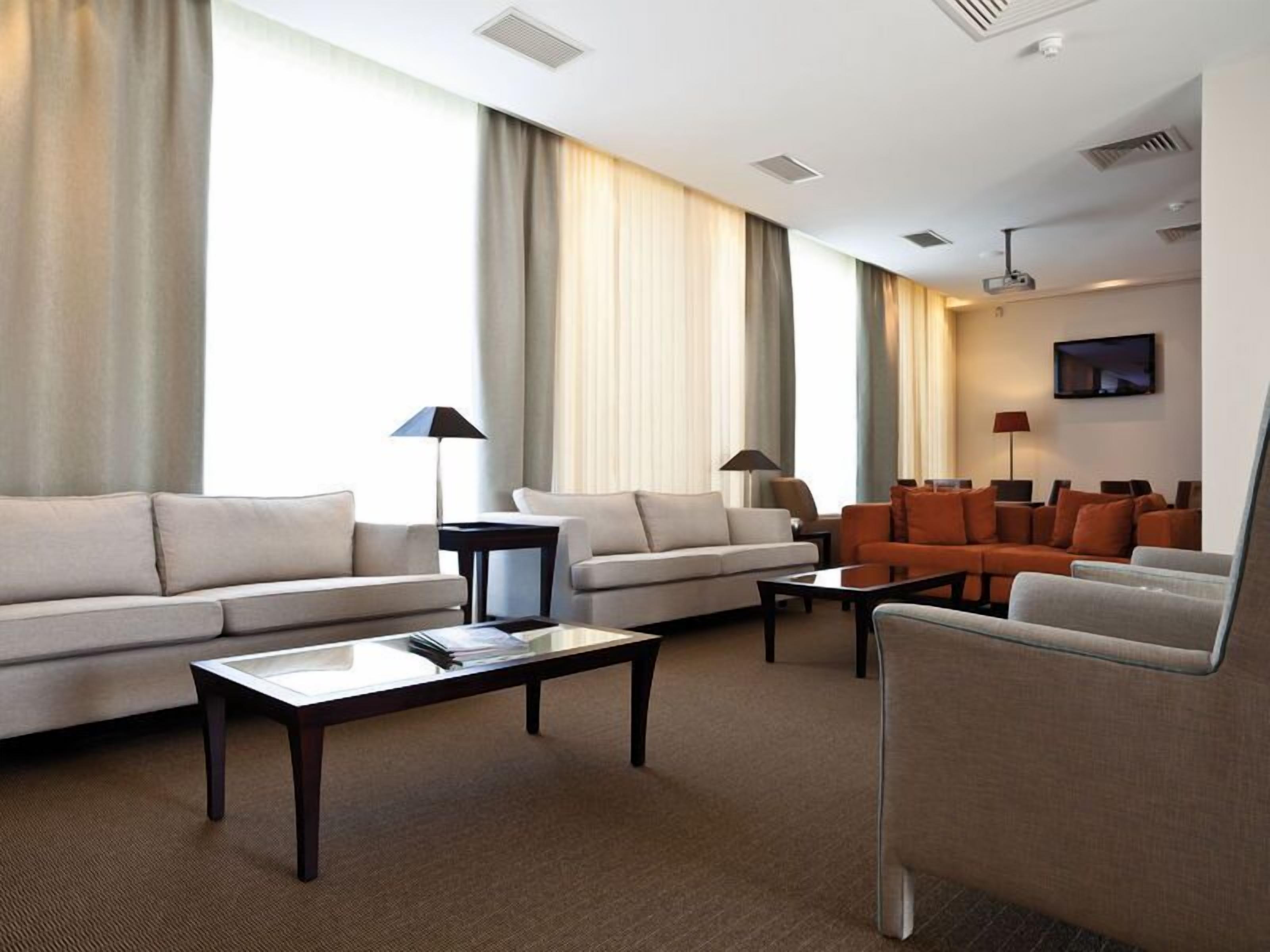 Un soggiorno moderno di un hotel con due divani, un tavolino da caffè e una televisione.