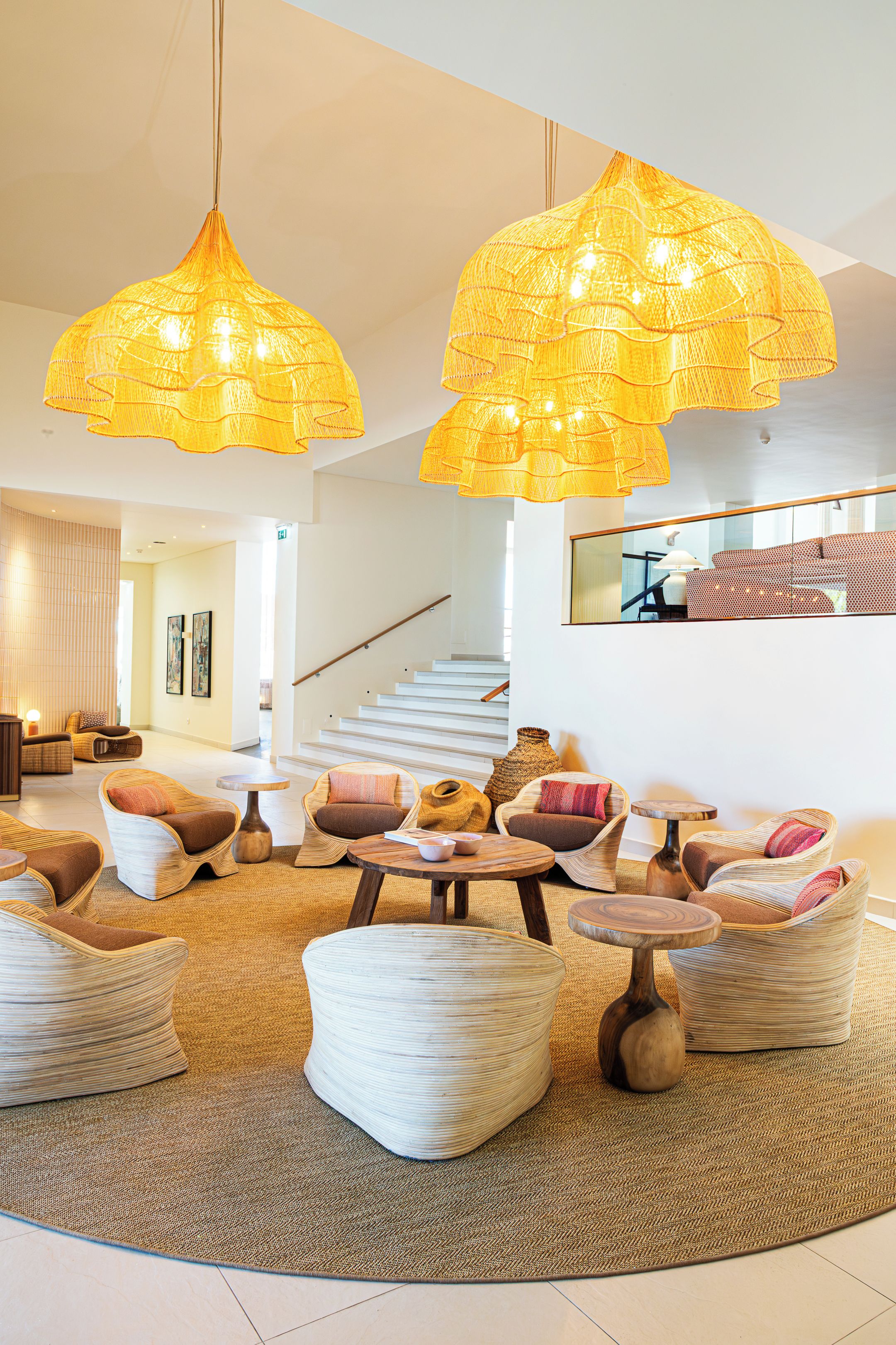 Uma sala de estar moderna com móveis de vime, uma luminária trançada grande e uma escada.