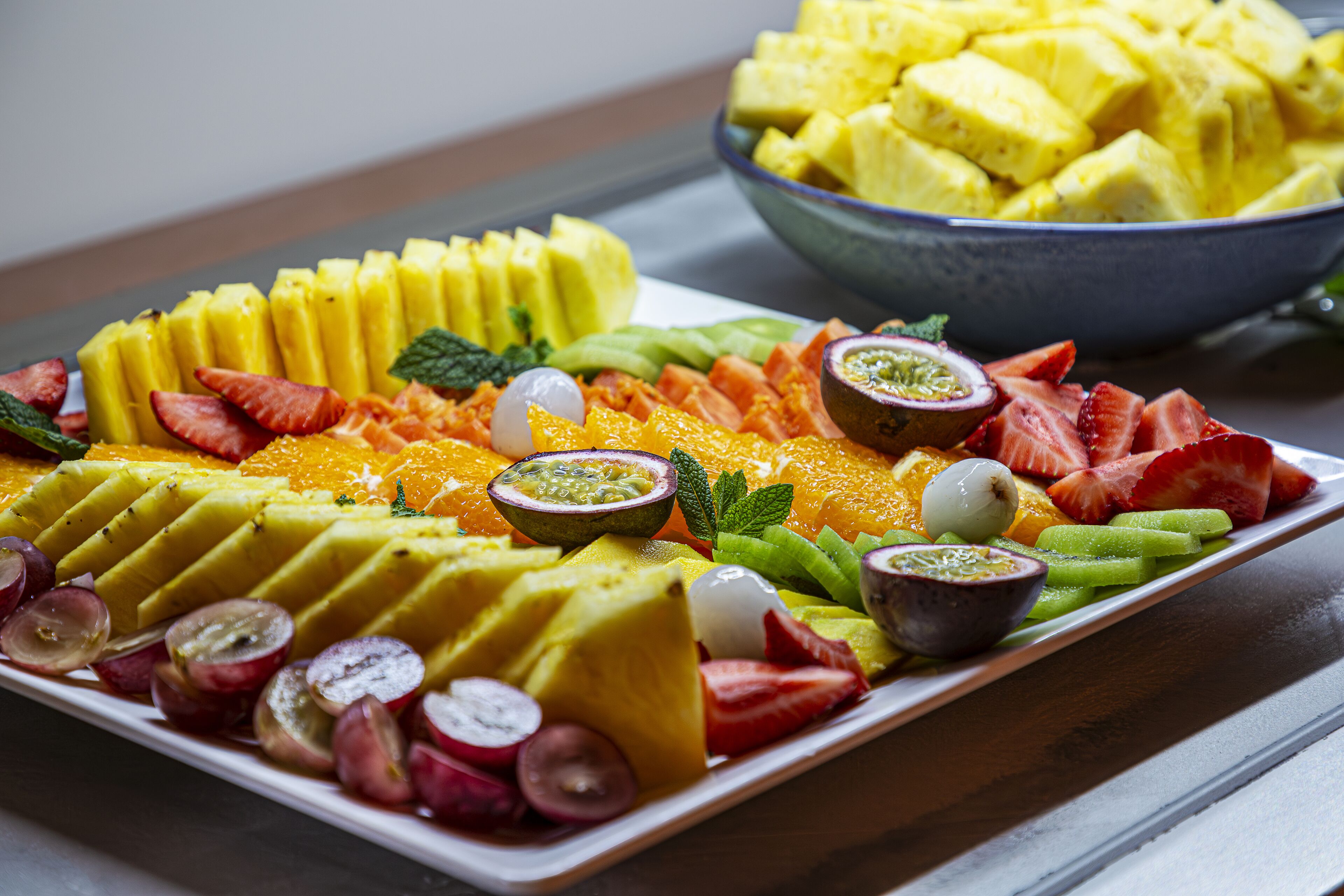 Eine Obstplatte mit verschiedenen Früchten wie Mango, Erdbeeren und Kiwi.