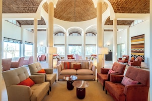 A spacious lobby with high ceilings, large windows, and a central seating area with multiple sofas and armchairs.