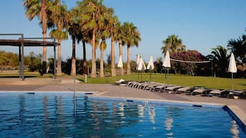 Una piscina techada, una piscina al aire libre, sombrillas