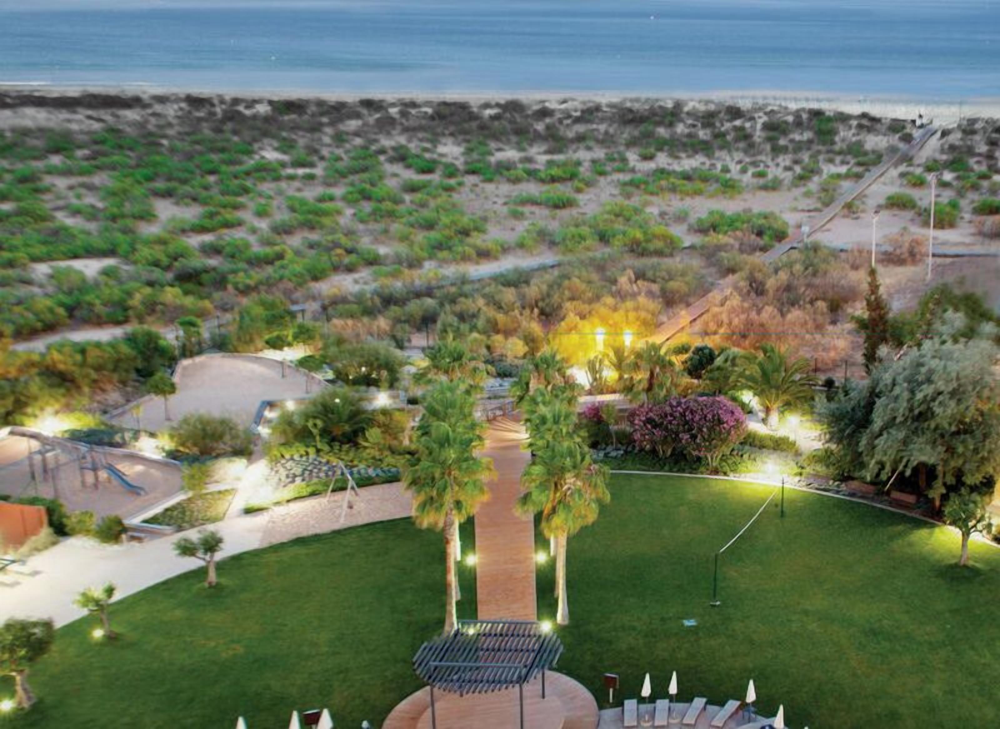 A landscaped garden with pathways, seating areas, and a view of the beach.