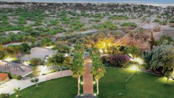 Un jardín ajardinado con senderos, zonas de estar y vistas a la playa.