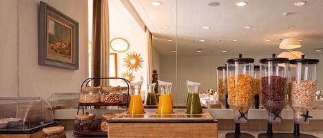 A breakfast buffet with various food items and beverages, including cereals, fruits, and juices.