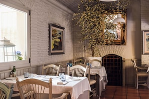 A dining area with white brick walls, wooden chairs, and tables set for a meal. - Hotel Pirineo Figueres by Pierre and Vacances (Figueres)