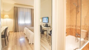A hotel room with a bed, a desk, a TV, and a shower area. - Hotel Pirineo Figueres by Pierre and Vacances (Figueres)