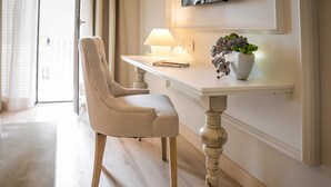 A room with a beige upholstered chair, a white console table with a lamp and a potted plant, and a wooden floor. - Hotel Pirineo Figueres by Pierre and Vacances (Figueres)