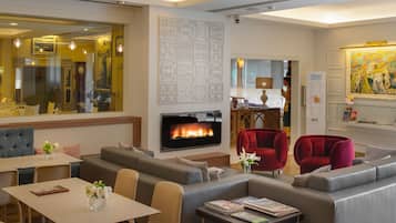 Un moderno vestíbulo de hotel con chimenea, zonas de estar y un espacio para comer.