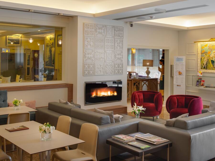 Een moderne hotel lobby met een open haard, zithoeken en een eetgedeelte.