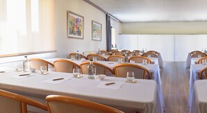 A conference room with tables set for meetings, equipped with chairs, water bottles, and glassware.