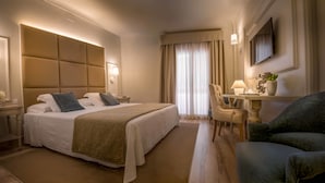 A hotel room with a large bed, a desk with a lamp, a chair, and a TV on the wall. - Hotel Pirineo Figueres by Pierre and Vacances (Figueres)