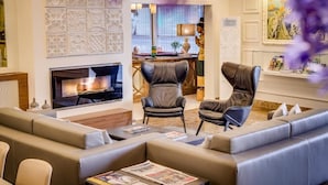 A modern living room with a fireplace, leather armchairs, a sofa, and a decorative wall. - Hotel Pirineo Figueres by Pierre and Vacances (Figueres)
