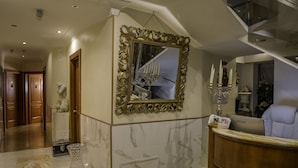 A hotel lobby with marble flooring, a reception desk, a large ornate mirror, and a staircase. - Luxury Rooms H 2000 Roma (Rome)