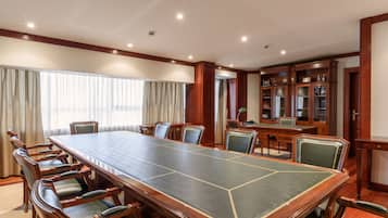 A conference room with a long table, chairs, and a cabinet with glass doors.
