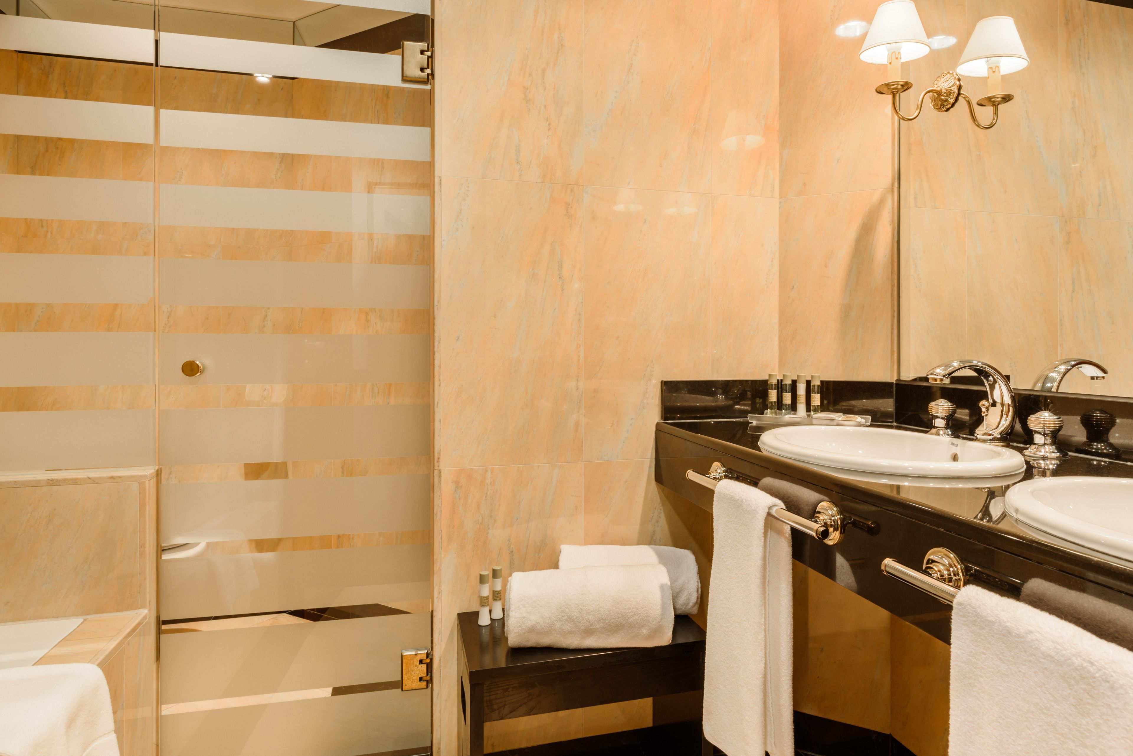 A modern bathroom with a glass shower enclosure, a vanity with a sink, and a large mirror.