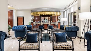 A lobby with a reception desk, seating area with sofas and chairs, and a large mirror. - Eurostars Gran Hotel Santiago (Santiago de Compostela)