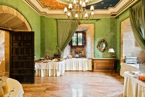 A banquet hall with a long table set for a meal, a chandelier, and a mirror on the wall. - Abba Palacio de Soñanes Hotel (Villacarriedo)