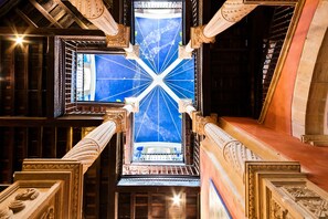 A grand architectural interior with ornate columns, a central skylight, and a view of the sky through a patterned window. - Abba Palacio de Soñanes Hotel (Villacarriedo)