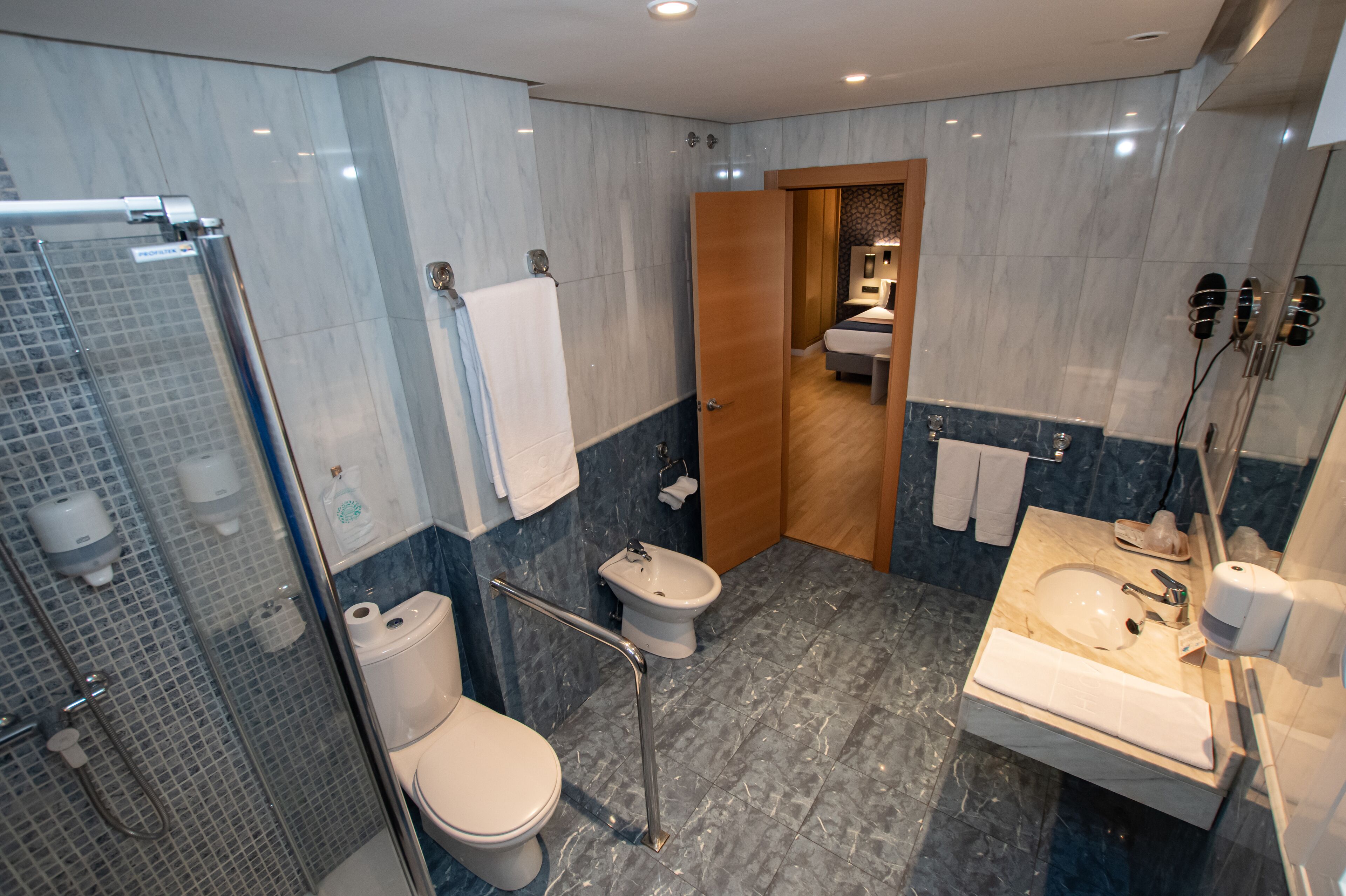 Un baño moderno con cabina de ducha de vidrio, inodoro, bidé y lavamanos con espejo.