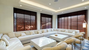 A modern living room with a sectional sofa, two coffee tables, and a patterned rug. - Sercotel Hotel Pozuelo (Pozuelo de Alarcon)