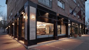 A modern building with large windows, a reception area, and outdoor seating. - Sercotel Hotel Pozuelo (Pozuelo de Alarcon)
