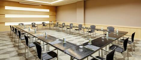 Ein Konferenzraum mit langem Tisch, Stühlen und einer Projektionsleinwand.