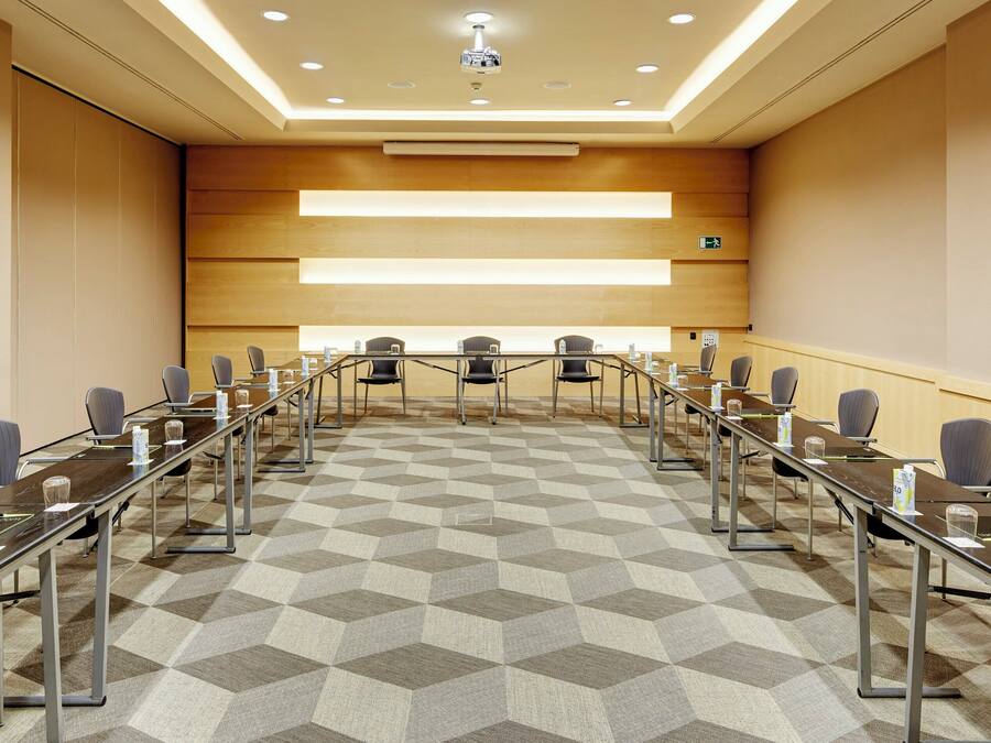 A conference room with a long table, chairs, and a projector screen.