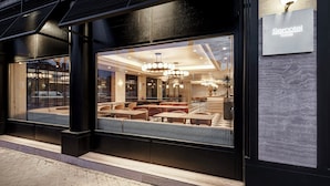 A hotel entrance with a modern design, large windows, and a visible seating area inside. - Sercotel Hotel Pozuelo (Pozuelo de Alarcon)