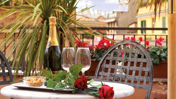 A table with a bottle of champagne, two glasses, a plate with food, and a red rose. - Hotel Novecento (Rome)