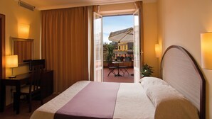 A hotel room with a bed, desk, chair, and a view of the outside balcony. - Hotel Novecento (Rome)