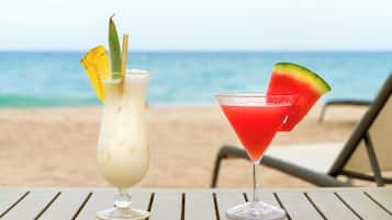 Two drinks on a table with a beach and ocean in the background.