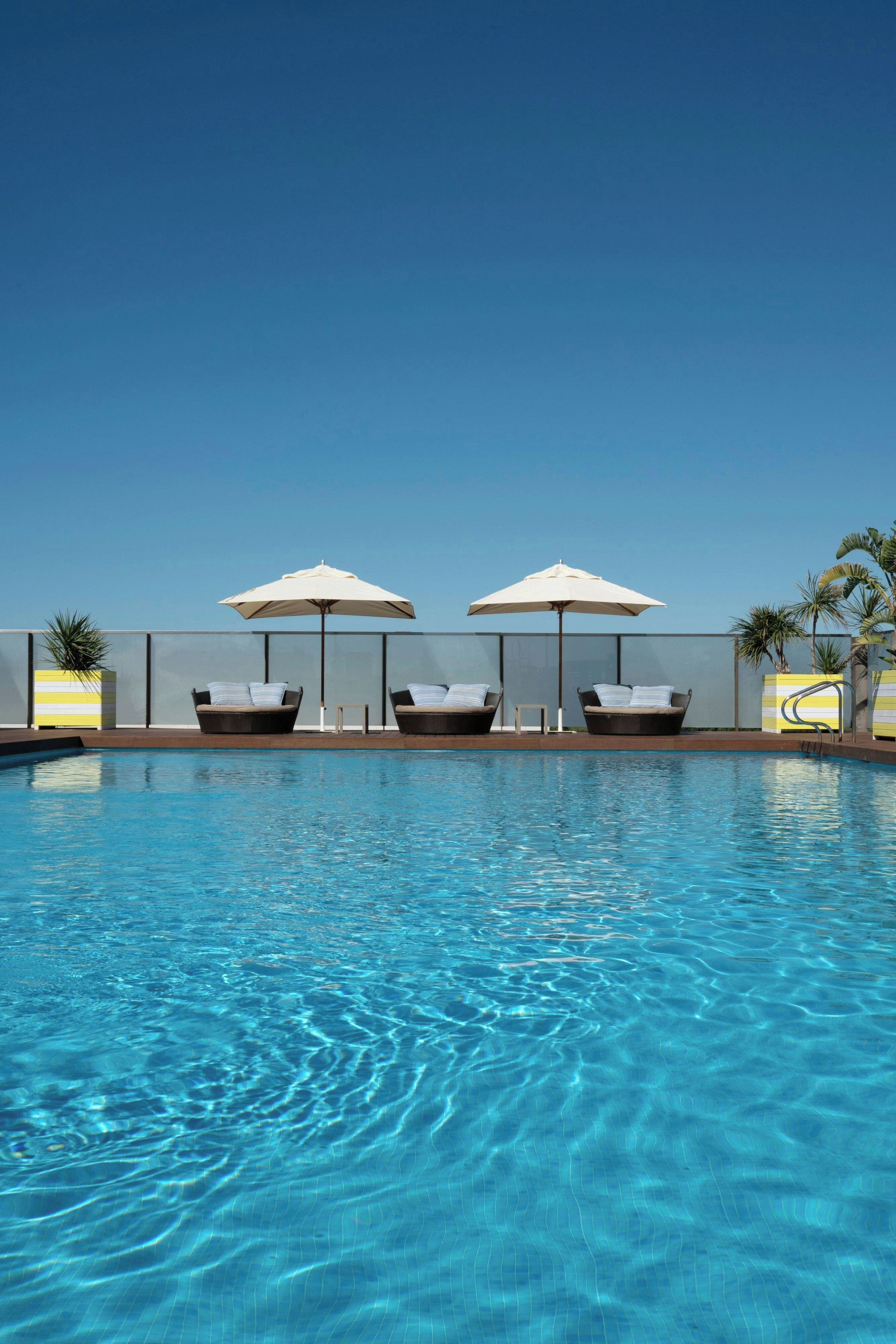 A swimming pool with lounge chairs and umbrellas.