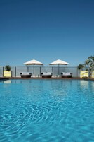 A swimming pool with lounge chairs and umbrellas.