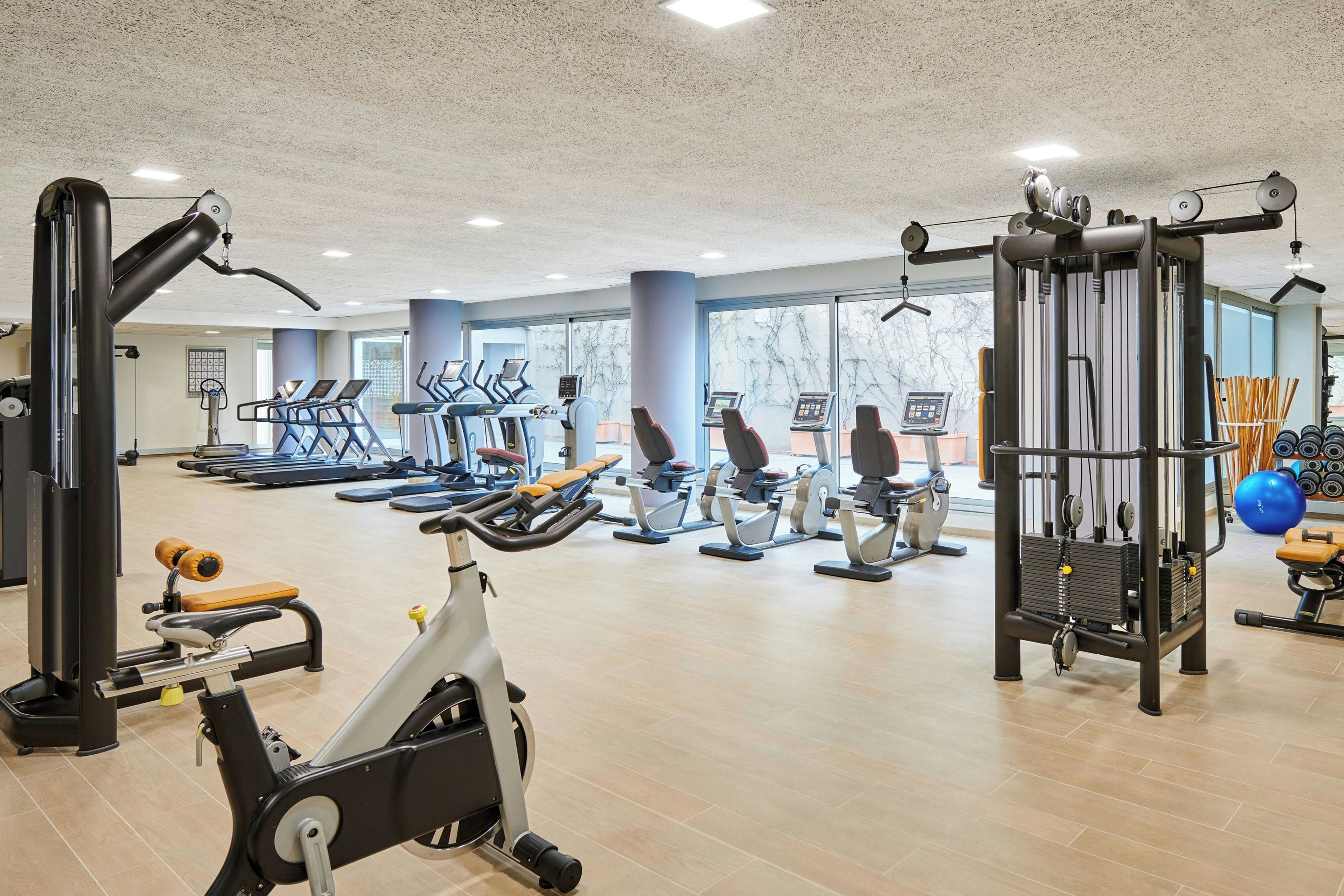 Una palestra con diverse attrezzature per l'allenamento, tra cui tapis roulant, cyclette e macchinari per pesi.