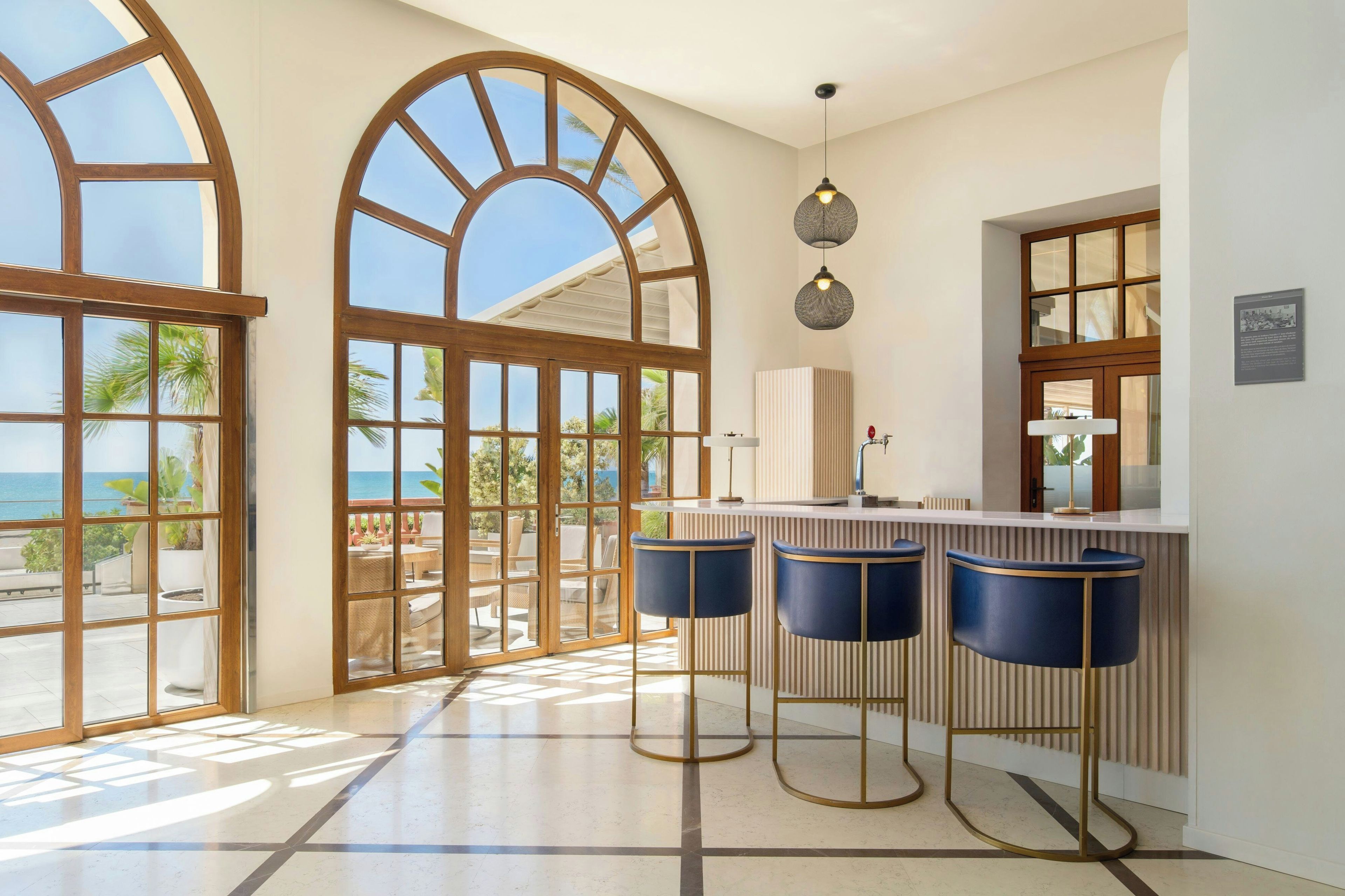 A spacious kitchen with large windows, a bar area with stools, and a view of the ocean.