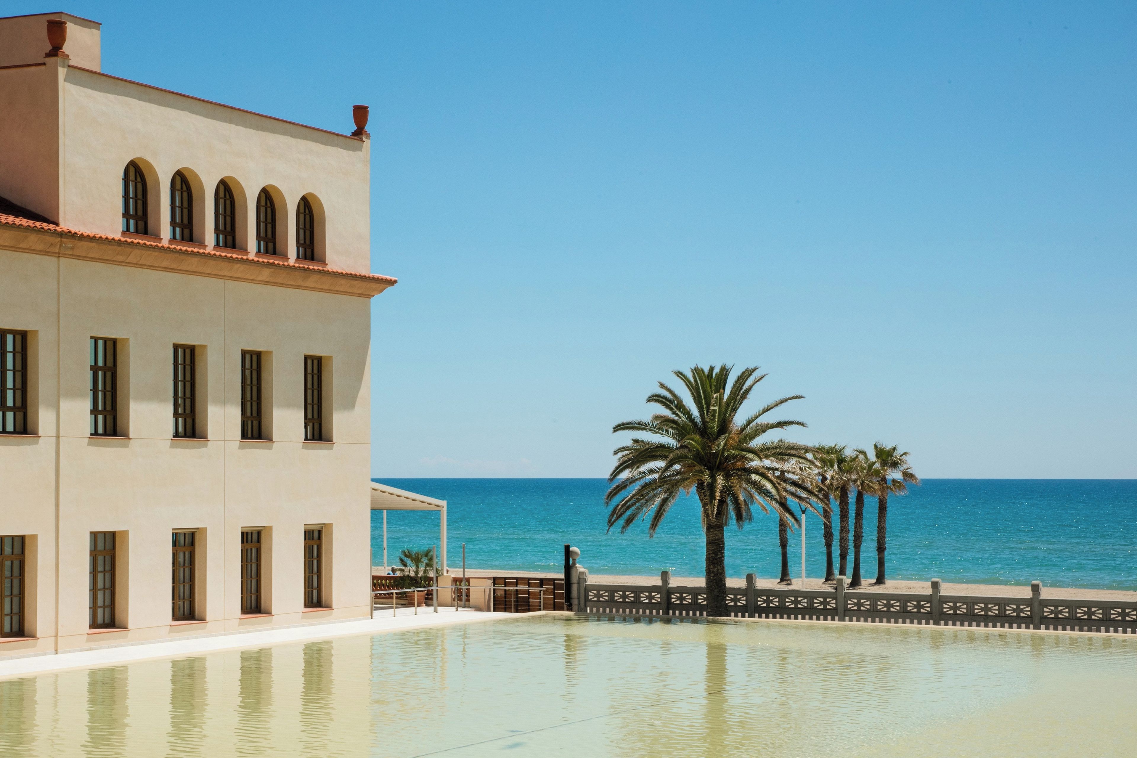 A building with a pool and a view of the sea.