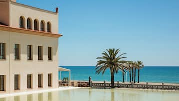 A building with a pool and a view of the sea.