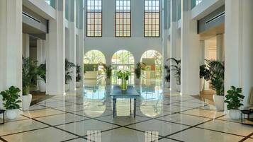 Eine großzügige Lobby mit hohen Decken, großen Bogenfenstern und einer zentral gelegenen Sitzecke.