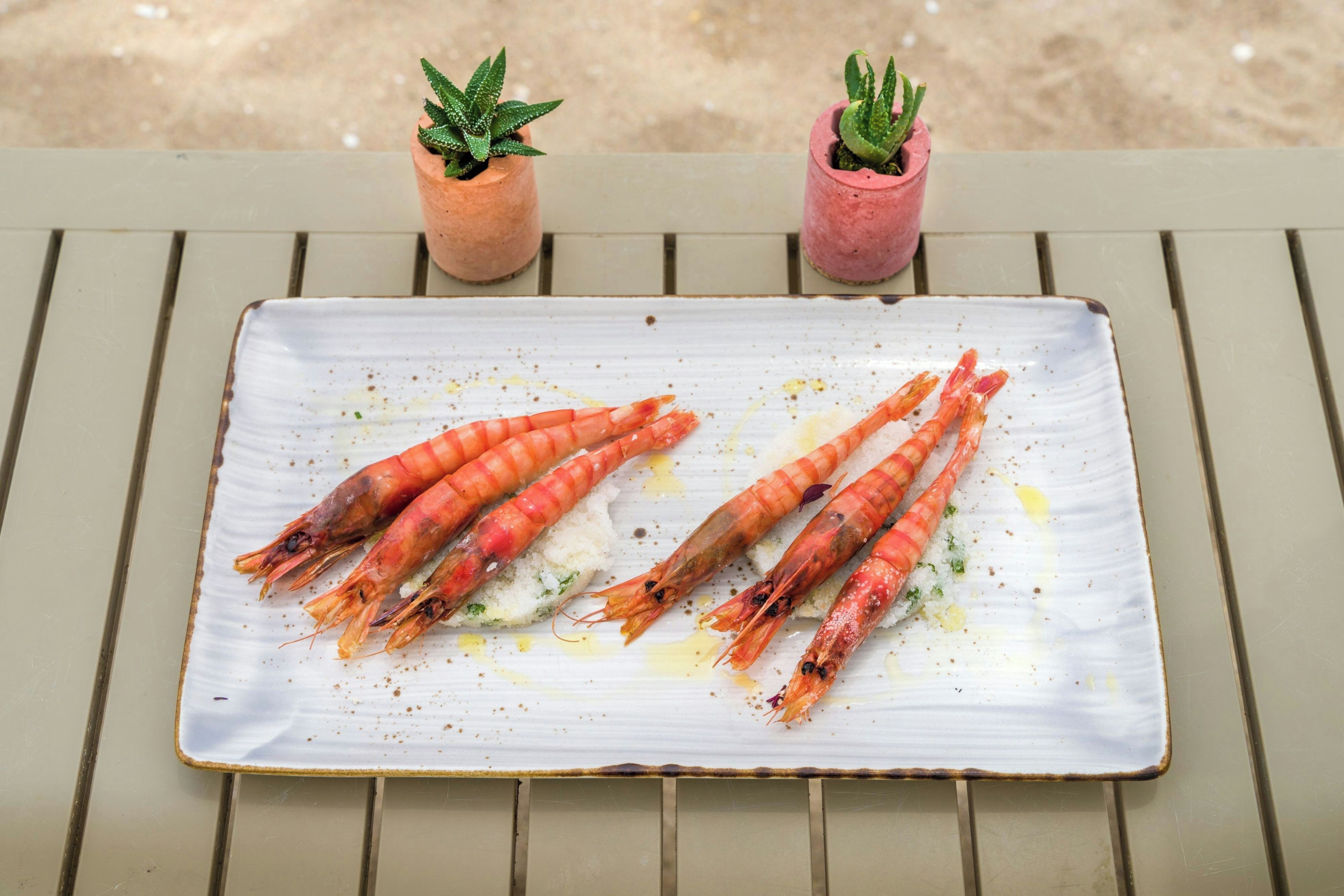 A white plate with cooked shrimp on a green table.