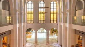 Un interior espacioso con techos altos, ventanas de arco y suelo de baldosas.