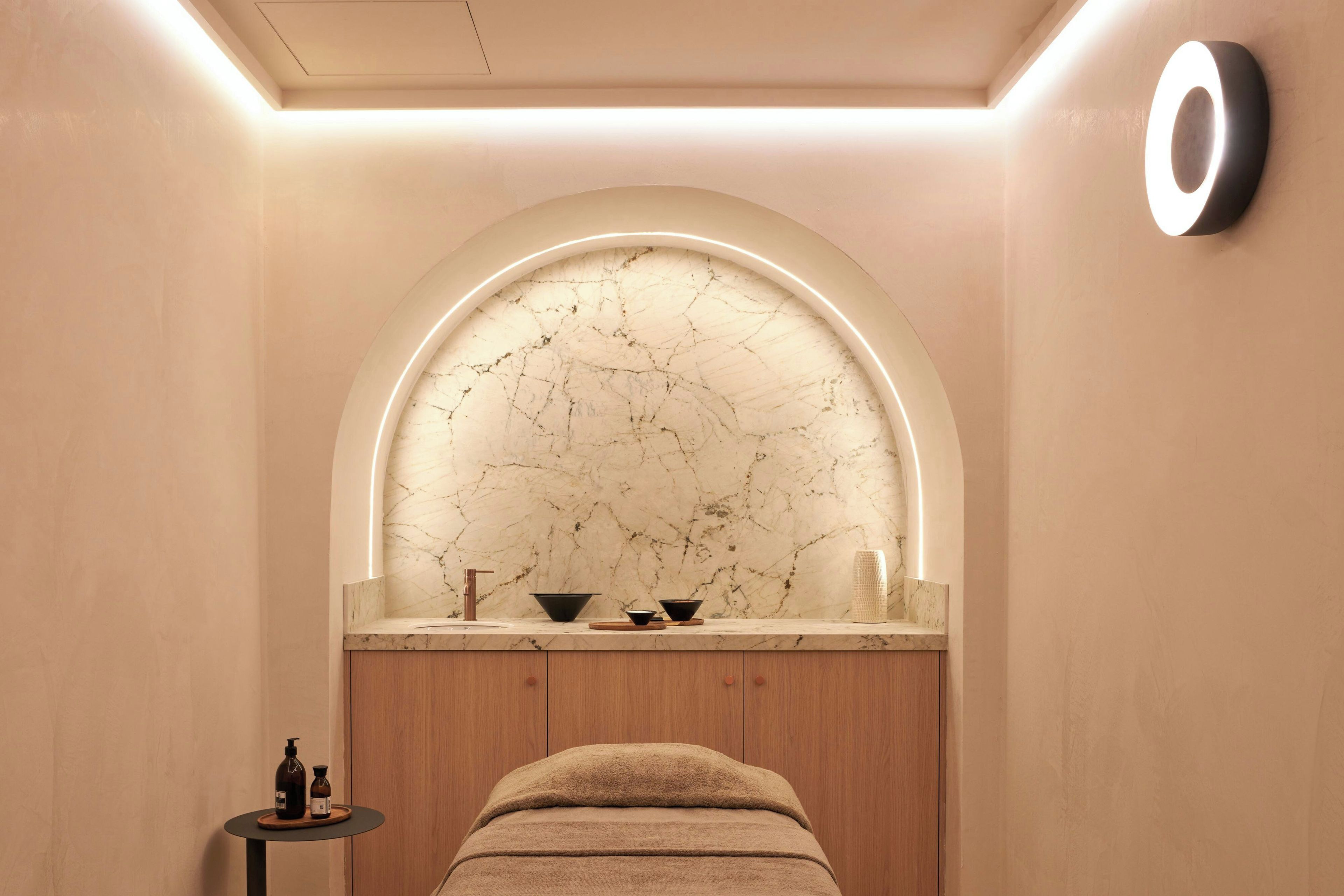 Een sparuimte met een marmeren wand, houten kasten en een massagetafel.