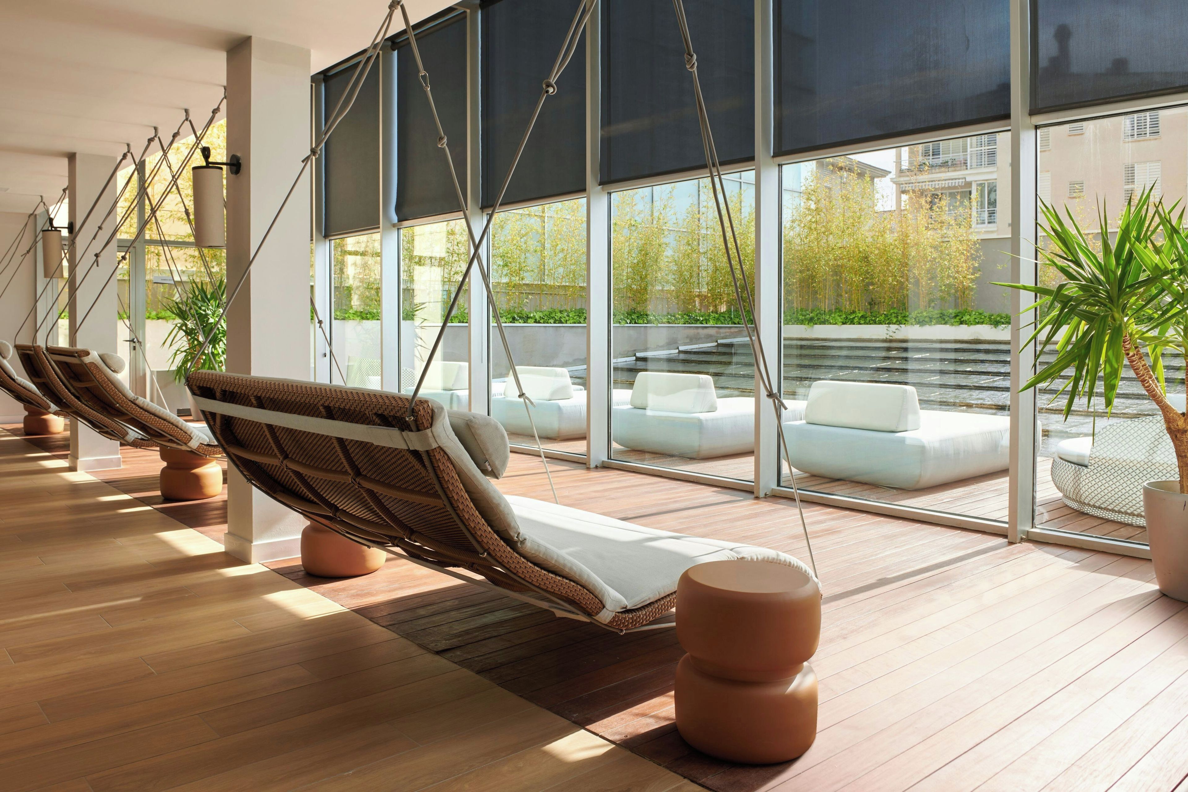 Een moderne loungehoek met rieten fauteuils en een groot raam met uitzicht op de omgeving.